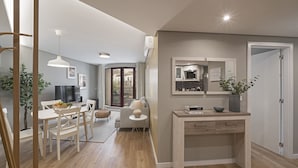 Een moderne woonkamer met een eethoek, een keuken met een ingebouwde magnetron en een groot raam.
