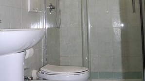 A bathroom with two toilets, a sink, and a glass-enclosed shower area. - Double Room (Roma)
