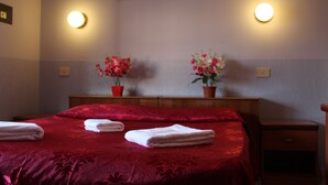 A hotel room with a large bed, two bedside tables, and two wall-mounted lamps. - Double Room (Roma)