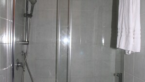 A glass-enclosed shower stall with a handheld showerhead, a glass door, and a white towel hanging on a rack. - Double Room (Roma)