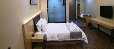 A hotel room with a bed, bedside tables, a TV, and a mirror.