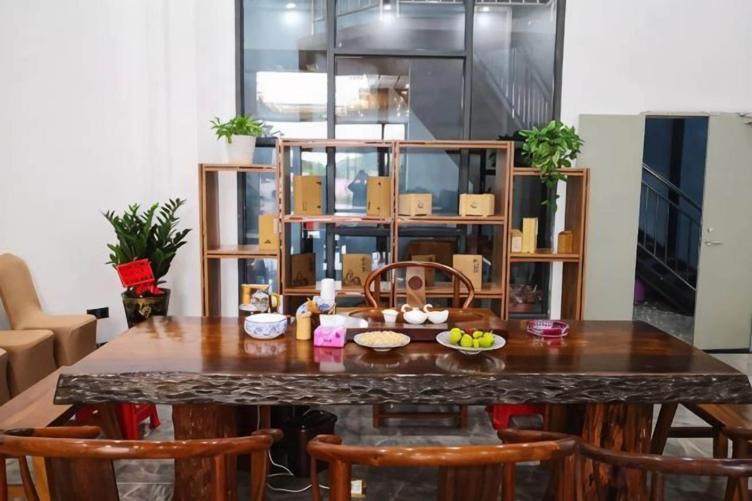 Un comedor con mesa de madera, sillas y un separador de vidrio con estantes.
