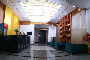 Un vestíbulo de hotel con una recepción, área de descanso y una amplia estantería.