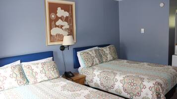 A bedroom with two beds, a nightstand, a lamp, and a framed picture on the wall.