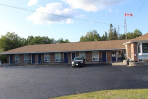 A motel with a brick facade, multiple rooms, and a parking lot.