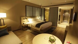 A modern hotel room with a large bed, bedside tables, a round coffee table, and a TV. - Echarm Hotel (Hong'an Zidong Xincheng) (Hong'an)