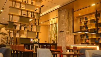 A modern interior with seating areas, bookshelves, and a decorative column.