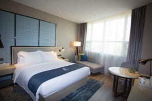 A hotel room with a large bed, a sofa, a small table, and a window with curtains. - Echarm Hotel (Hong'an Zidong Xincheng) (Hong'an)