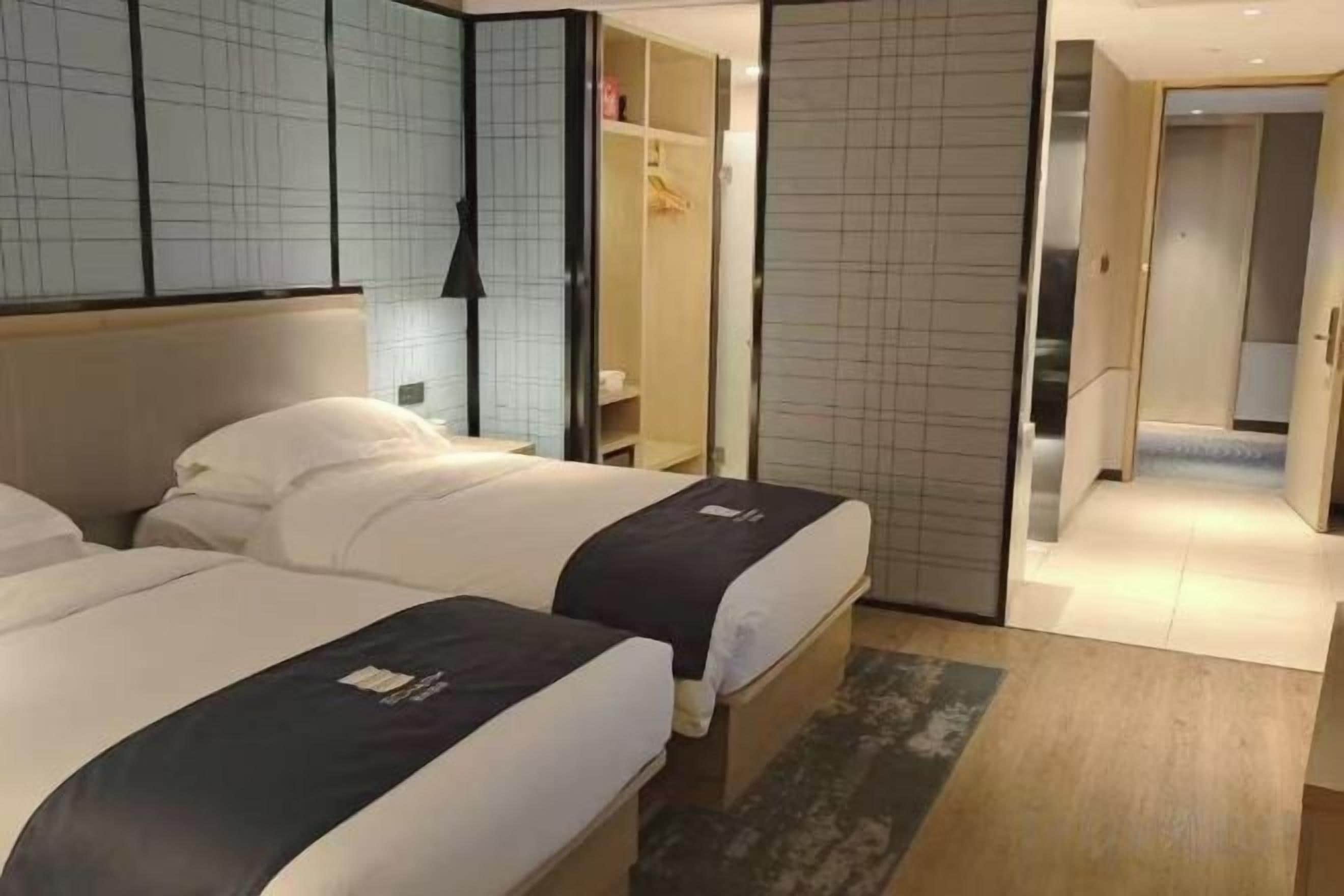 Hotellihuone, jossa on kaksi sänkyä, vaatekaappi ja kylpyhuone.