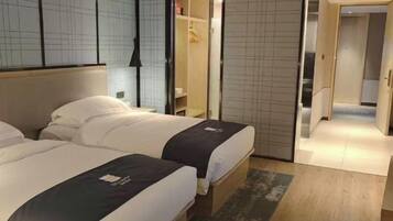 A hotel room with two beds, a wardrobe, and a bathroom.