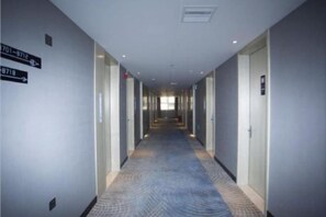 A hotel corridor with directional signs, doors, and a patterned carpet.