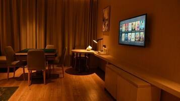 A hotel room with a pool table, a bar area, and a television displaying movie options.