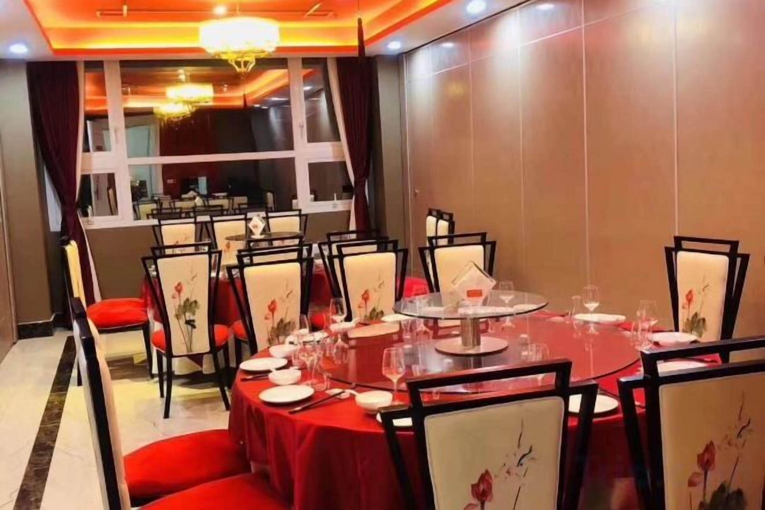 Un espace repas avec des tables rondes, des chaises et des nappes rouges.