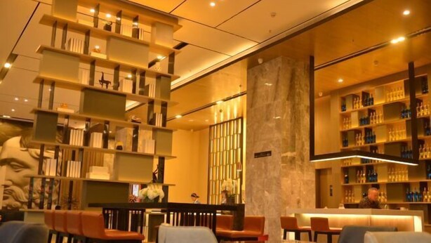 A modern interior with tiered bookshelves, a marble column, and a bar area. - Echarm Hotel (Hong'an Zidong Xincheng) (Hong'an)
