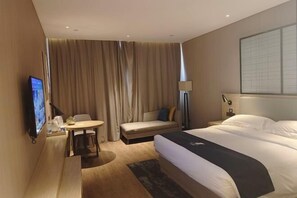 A hotel room with a bed, a sofa, a small table, a TV, and a window with curtains. - Echarm Hotel (Hong'an Zidong Xincheng) (Hong'an)