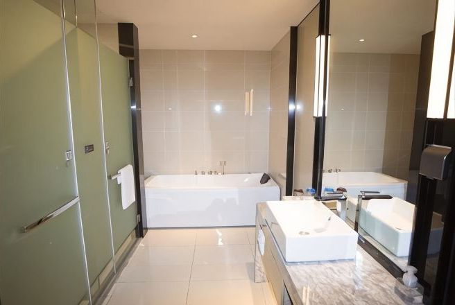 A modern bathroom with a large bathtub, a separate shower area, and a vanity with a mirror.
