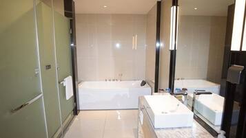 A modern bathroom with a large bathtub, a separate shower area, and a vanity with a mirror.