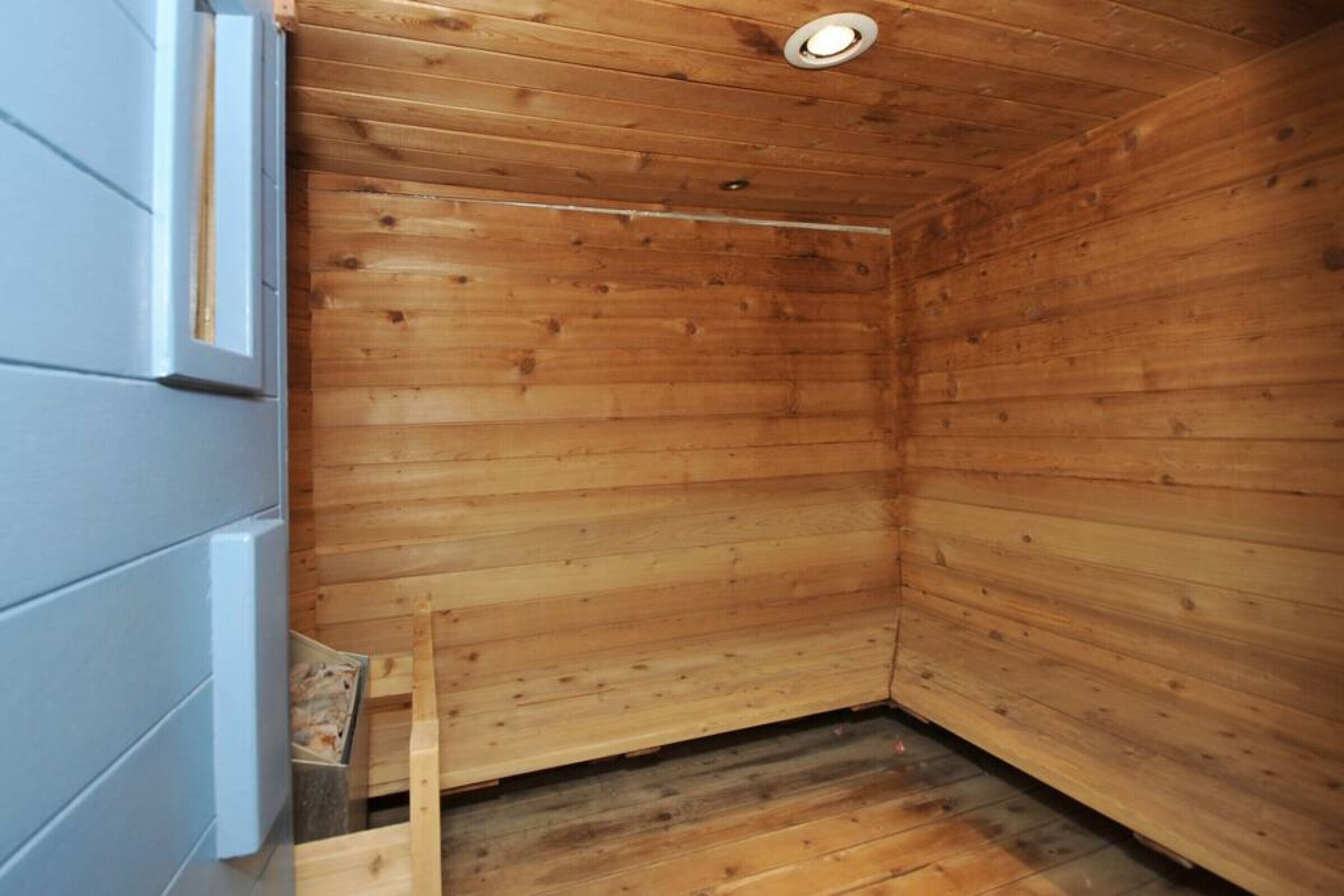 A wooden sauna with a sloped ceiling and a small window.