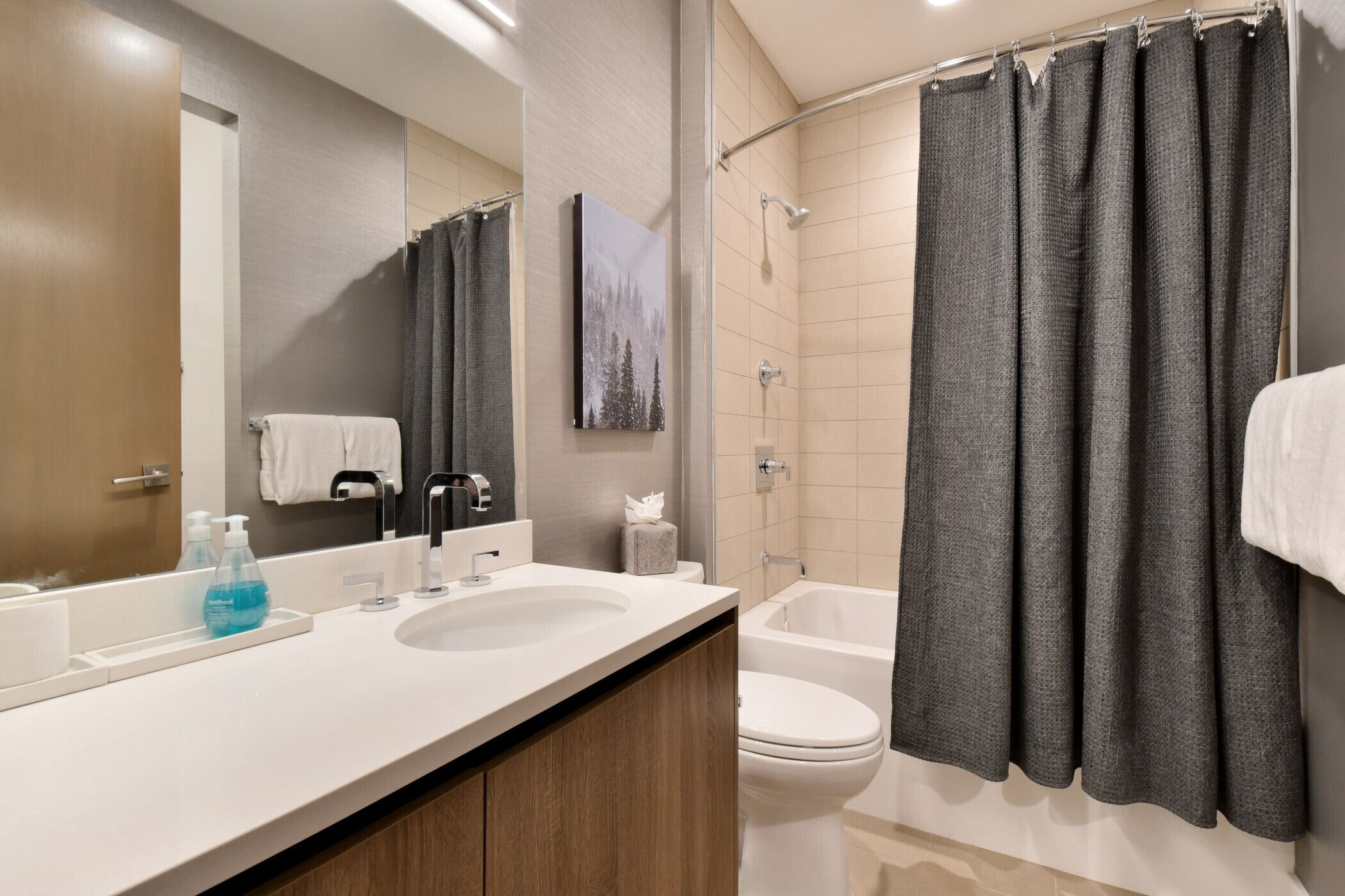 A modern bathroom with a double sink, a large mirror, a shower with a curtain, and a toilet.