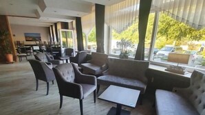 A spacious indoor area with a wooden floor, several sofas, a small table, and large windows offering a view of the outdoors. - Hotel Gasthof zum Ritter (Hassmersheim)