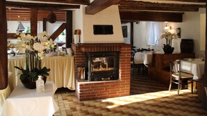 A rustic interior with a brick fireplace, wooden beams, a dining area, and a table with a vase of flowers. - Hotel Gasthof zum Ritter (Hassmersheim)