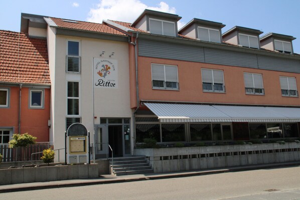 A hotel with a modern facade, a visible entrance, and a covered outdoor seating area.