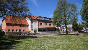 A hotel with a red-tiled roof, multiple windows, and a paved entrance area. - Hotel Gasthof zum Ritter (Hassmersheim)