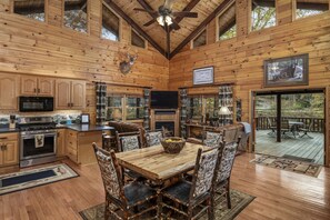 A wooden cabin interior with a dining area, kitchen, and a deck with outdoor furniture. - RIVER RUN - Blue Ridge, GA / Aska / Riverside & pet friendly! (Blue Ridge)