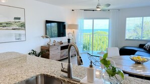A modern kitchen with a granite countertop, stainless steel sink, and a dining area with a table and chairs.