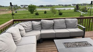 A deck with a gray sectional sofa and a small fire pit. - Large home on golf course, close to Seven Oaks, Ledges Park & ISU.  Sleeps 12+ (Boone)