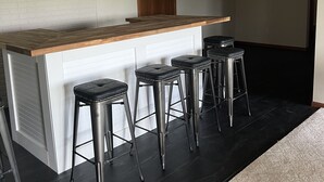 A kitchen with a bar area, four stools, and a wooden countertop. - Large home on golf course, close to Seven Oaks, Ledges Park & ISU.  Sleeps 12+ (Boone)