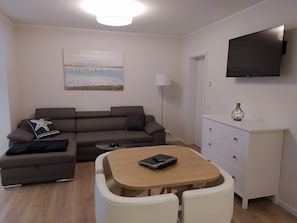 A modern living room with a sofa, a coffee table, and a TV mounted on the wall.