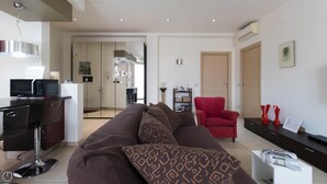 A modern living room with a brown sofa, a red armchair, and a dining area with a black table and chairs. - Italianway Easy - Dall Ongaro 24 (Milan)