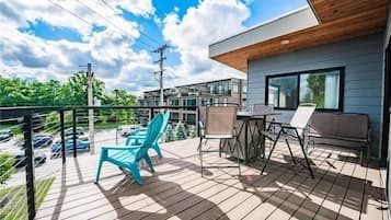 A deck with outdoor furniture, a view of the surrounding buildings, and a clear sky.