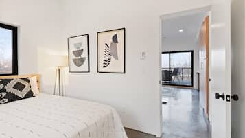 A bedroom with a bed, a nightstand, and two wall-mounted abstract paintings.