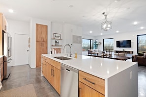 A modern kitchen with a central island, wooden cabinets, and a built-in dishwasher. - Lucky Duck-Skyline View of CLE/Short Walk Downtown (Cleveland)