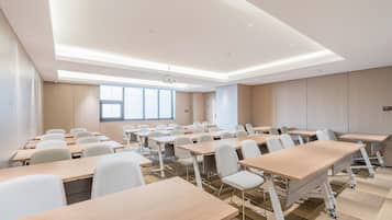 Un salón de conferencias con varias mesas y sillas, un proyector y un amplio ventanal.