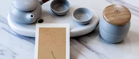 A tea set with a wooden-handled tea kettle, two teacups, and a teapot on a marble surface.