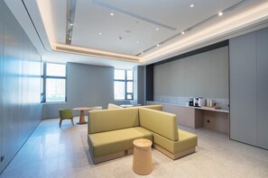 Un interior moderno con un sofá modular, una pequeña mesa redonda y una zona de kitchenette.