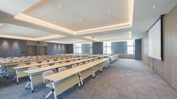 A conference room with rows of tables, a projector screen, and large windows.