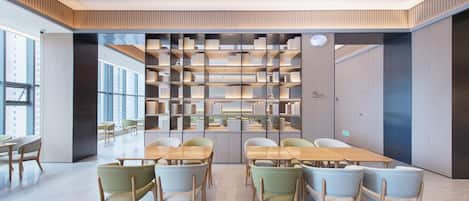 A modern library with bookshelves, a long table, and chairs.
