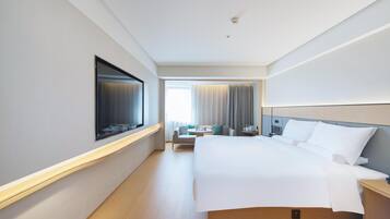 A hotel room with a bed, bedside table, TV, and a view of the hallway.