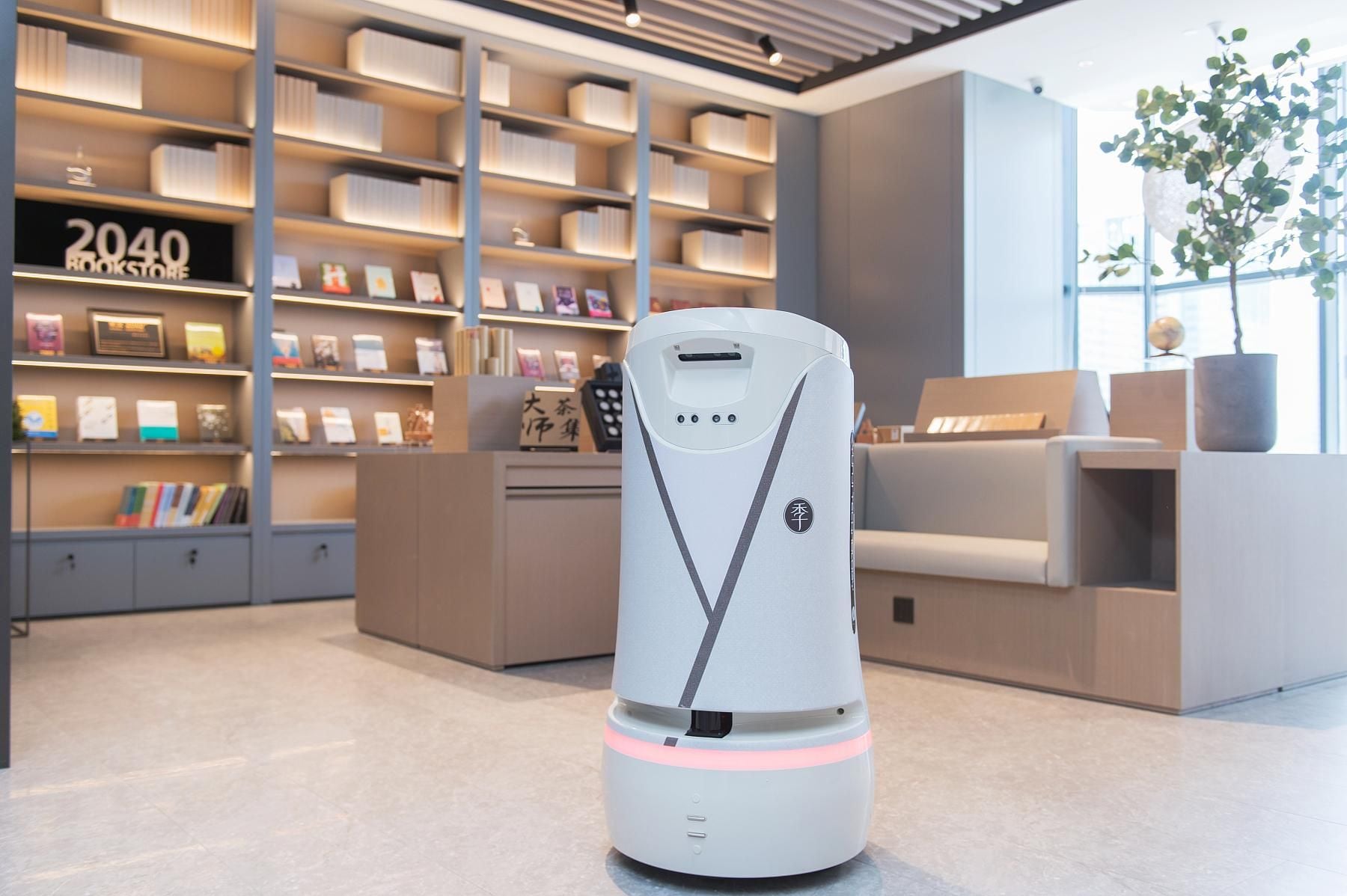 Un robot dans une librairie moderne et bien éclairée, avec des étagères remplies de livres et une enseigne indiquant « LIBRAIRIE 2040 ».