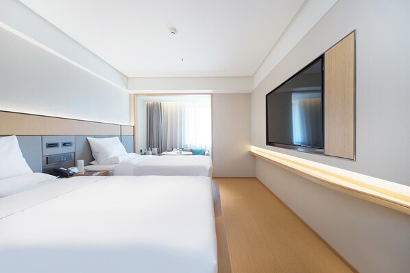A hotel room with two beds, a TV, a desk with a phone, and a window with curtains. - Ji Hotel (Dalian)