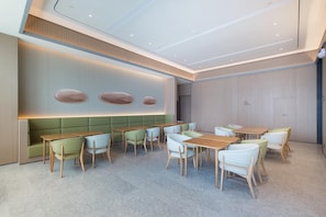 A modern interior with a seating area, tables, and a wall with decorative elements. - Ji Hotel (Dalian)