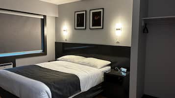 Un dormitorio moderno con una cama, mesitas de noche, un reloj en la pared y cuadros enmarcados.