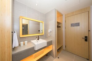 A modern bathroom with a large mirror, a sink, a towel rack, and a shower area. - Ji Hotel Xingtai Museum Store (Xingtai)