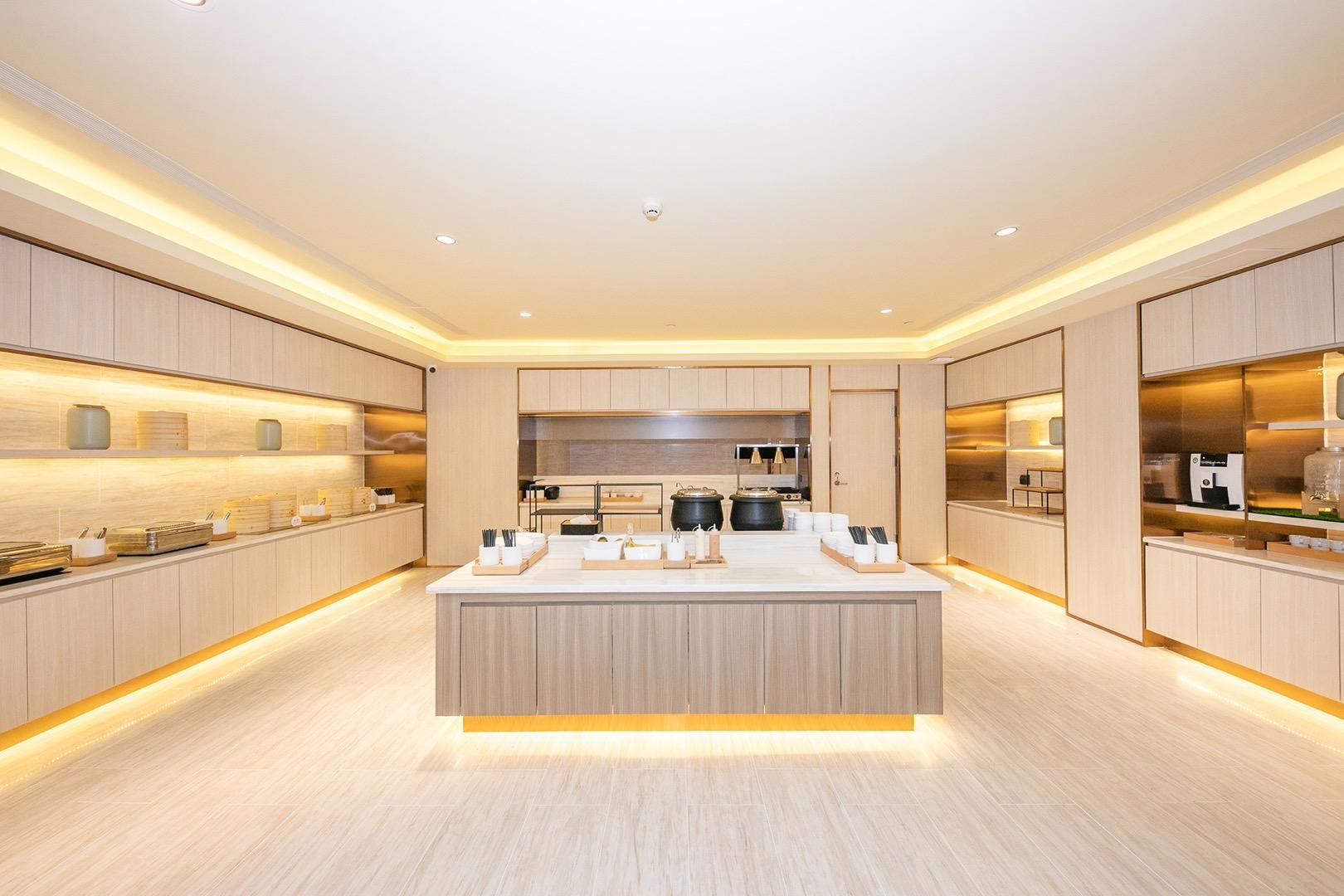 A modern kitchen with a central island, wooden cabinetry, and built-in appliances.