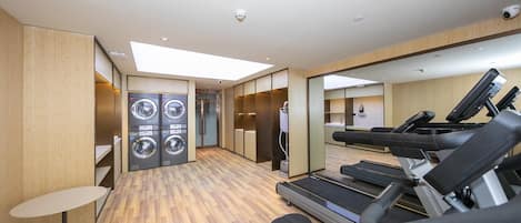 Un gimnasio con equipamiento de ejercicio, zona de duchas y mostrador de recepción.