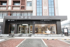 A hotel entrance with a revolving door, a glass facade, and a sign indicating 'JI HOTEL'.